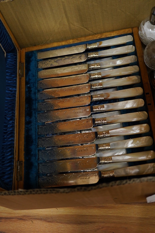 A cased set of twelve pairs of mother of pearl handled plated dessert eaters and a quantity of assorted plated items including a toastrack, a pair of mounted glass condiments, crumb scoop and miscellaneous flatware.